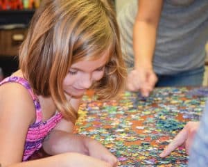 girl in pink tank top looking at jigsaw pieces