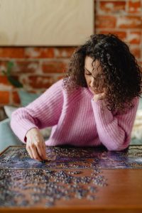 A Woman in a Pink Sweater doing a jigsaw puzzle