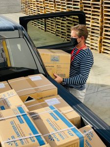 man in black and white striped long sleeve shirt loading boxes into a black car