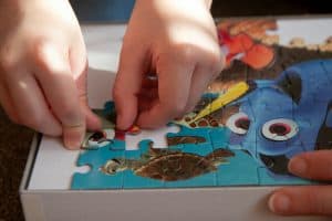 a person placing a jigsaw puzzle piece with both hands